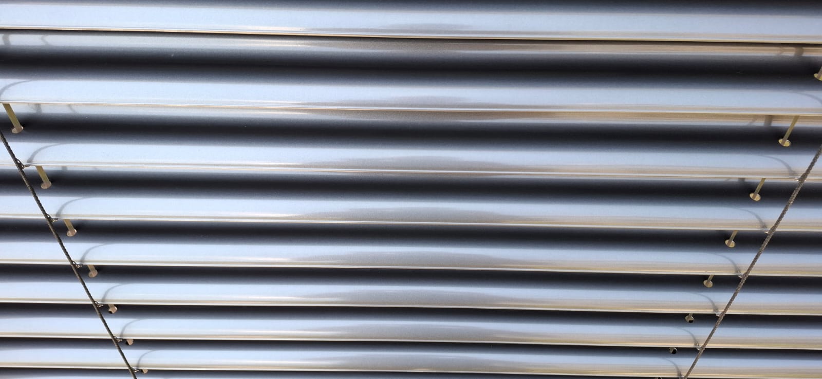 Nahaufnahme von sauberen Lamellen eines Rollladens an einem sonnigen Tag.