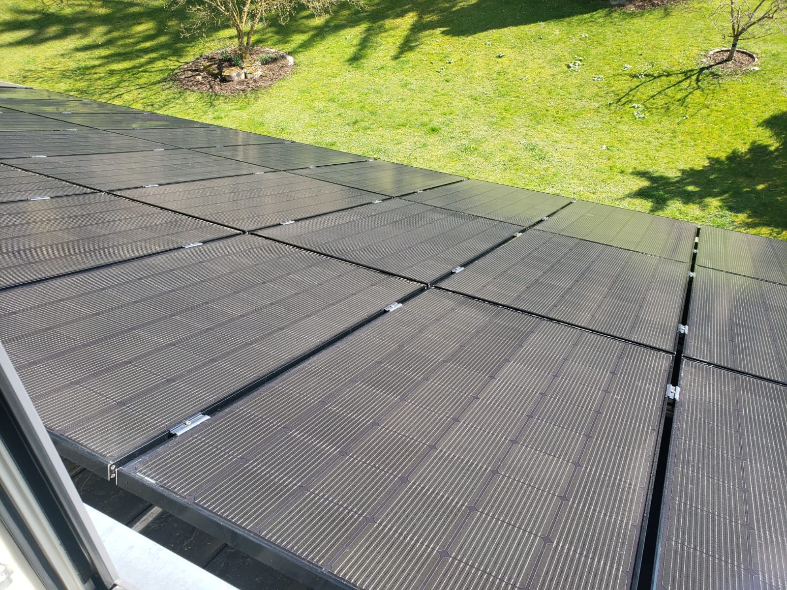 Aufnahme aus dem Fenster auf mehrere Solarpanels auf dem Dach eines Hauses.